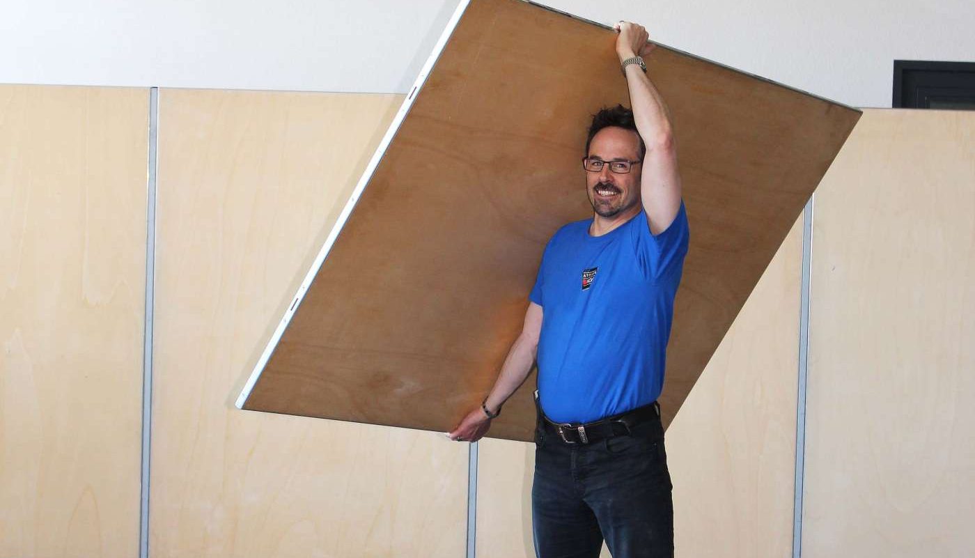 stellwaende-modelltische Mann hält PANO-Stellwand in die Höhe